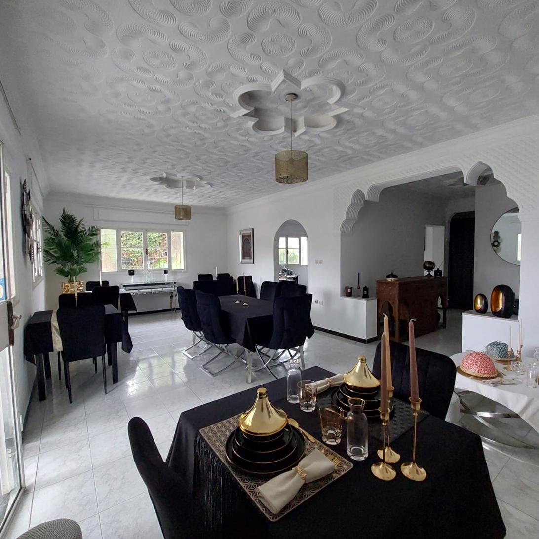 Salle à manger de Dar Kamilia avec arche mauresque, plafond travaillé et plusieurs tables dressées