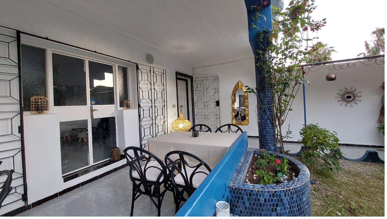 Terrasse couverte de Dar Kamilia avec table dressée, mosaïque bleu zellige et lanternes en laiton