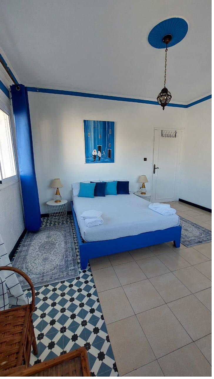 Chambre Mina : ambiance Chefchaouen avec mur et cadre bleus, zellige géométrique au sol