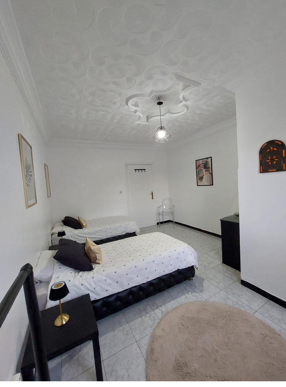 Chambre Zinedine : deux lits simples, plafond travaillé, ambiance épurée et lumineuse